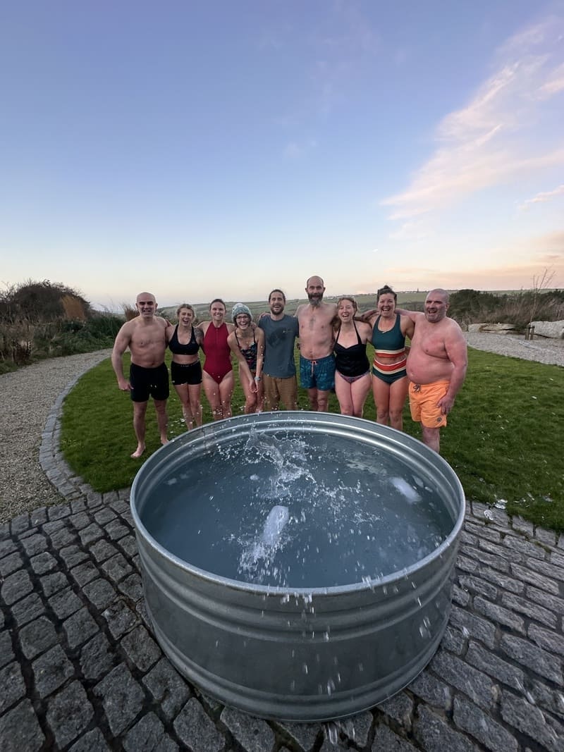 Group standing together after a Soul Sweats ice bath session at Mount Pleasant Eco Park, smiling beside the cold-water tub at sunset.