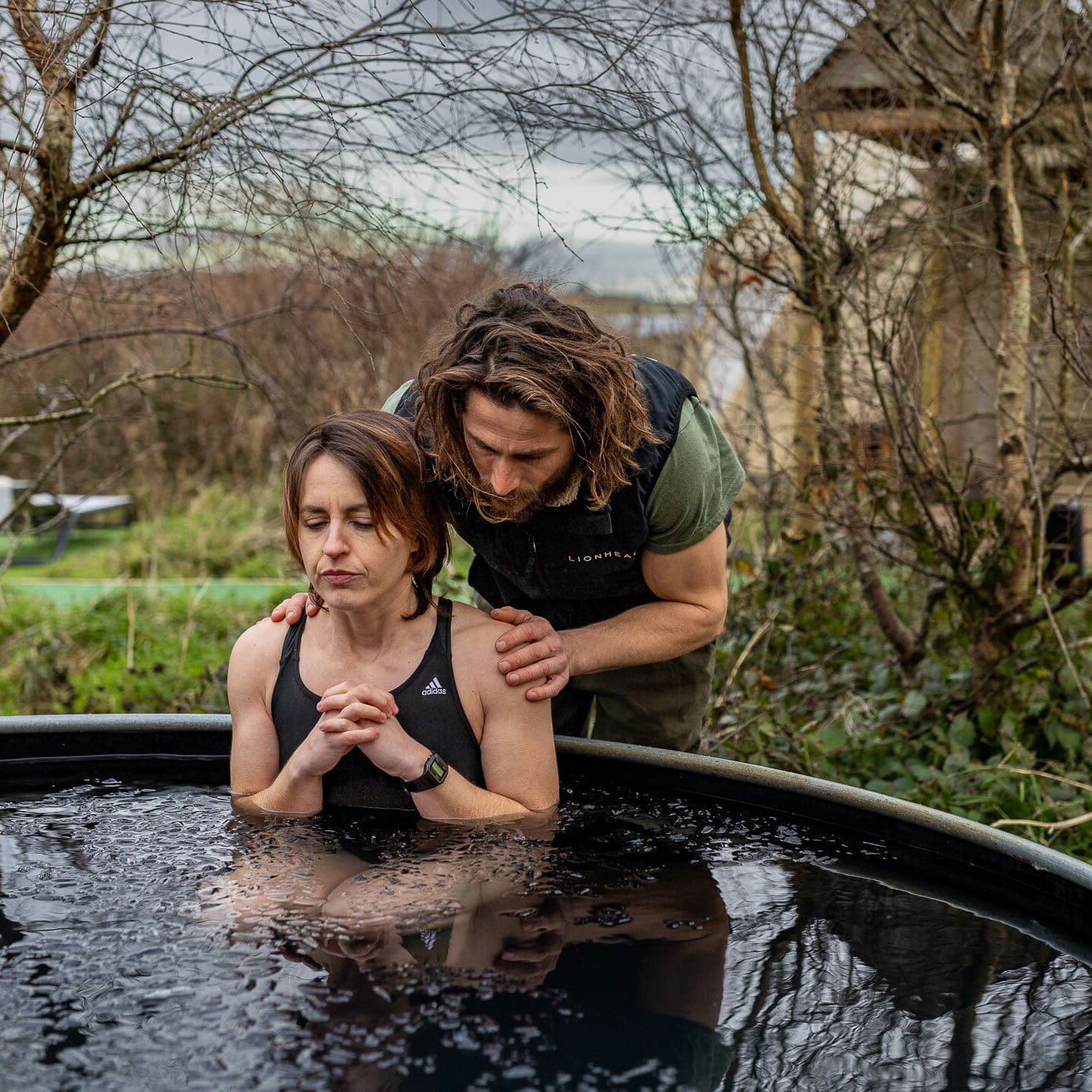 A Wim Hof Retreat, girl sitting in an icebath with a member helping her