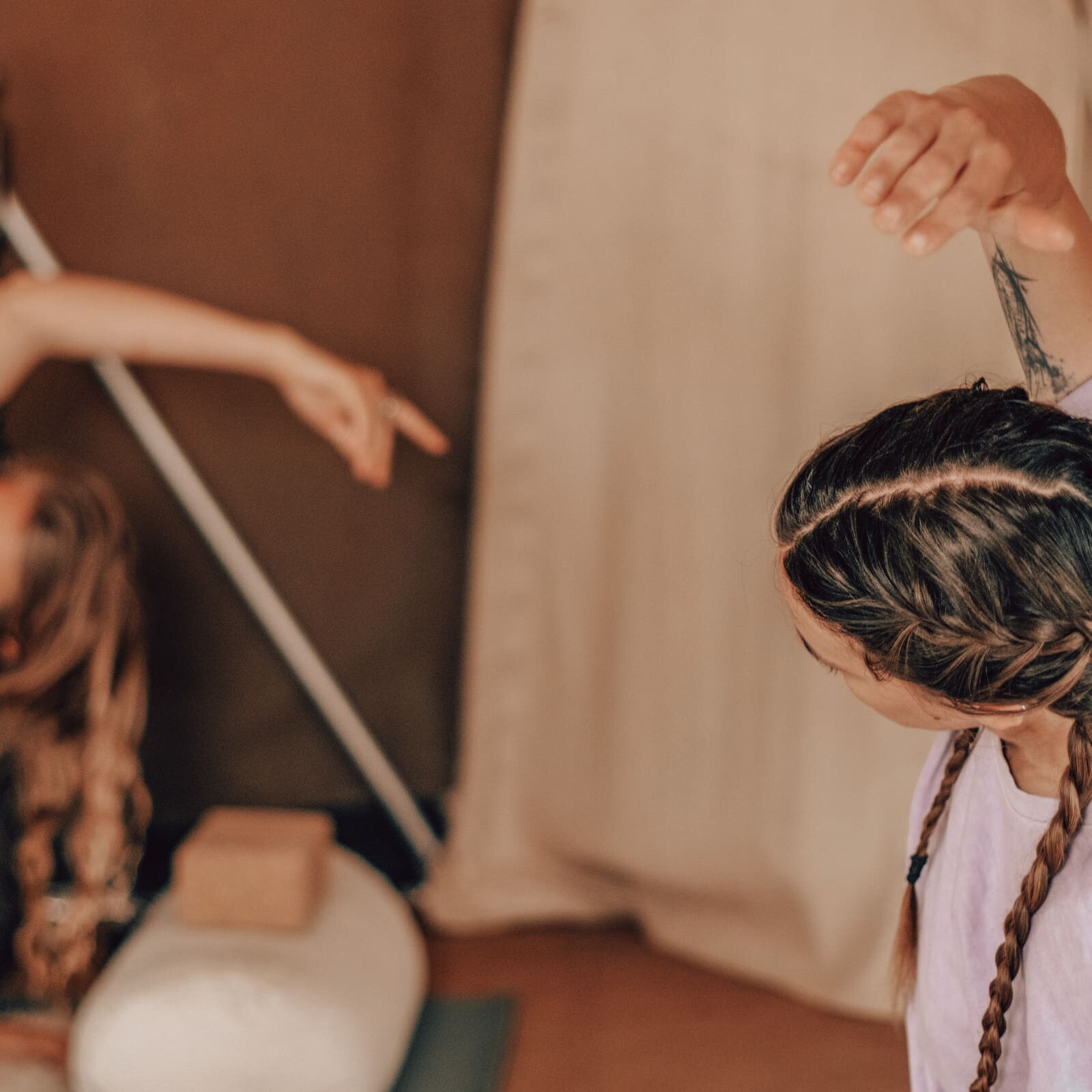Two women practising gentle Yin Yoga during a Soul Sweats holistic session, stretching with soft warm lighting in the canvas dome.