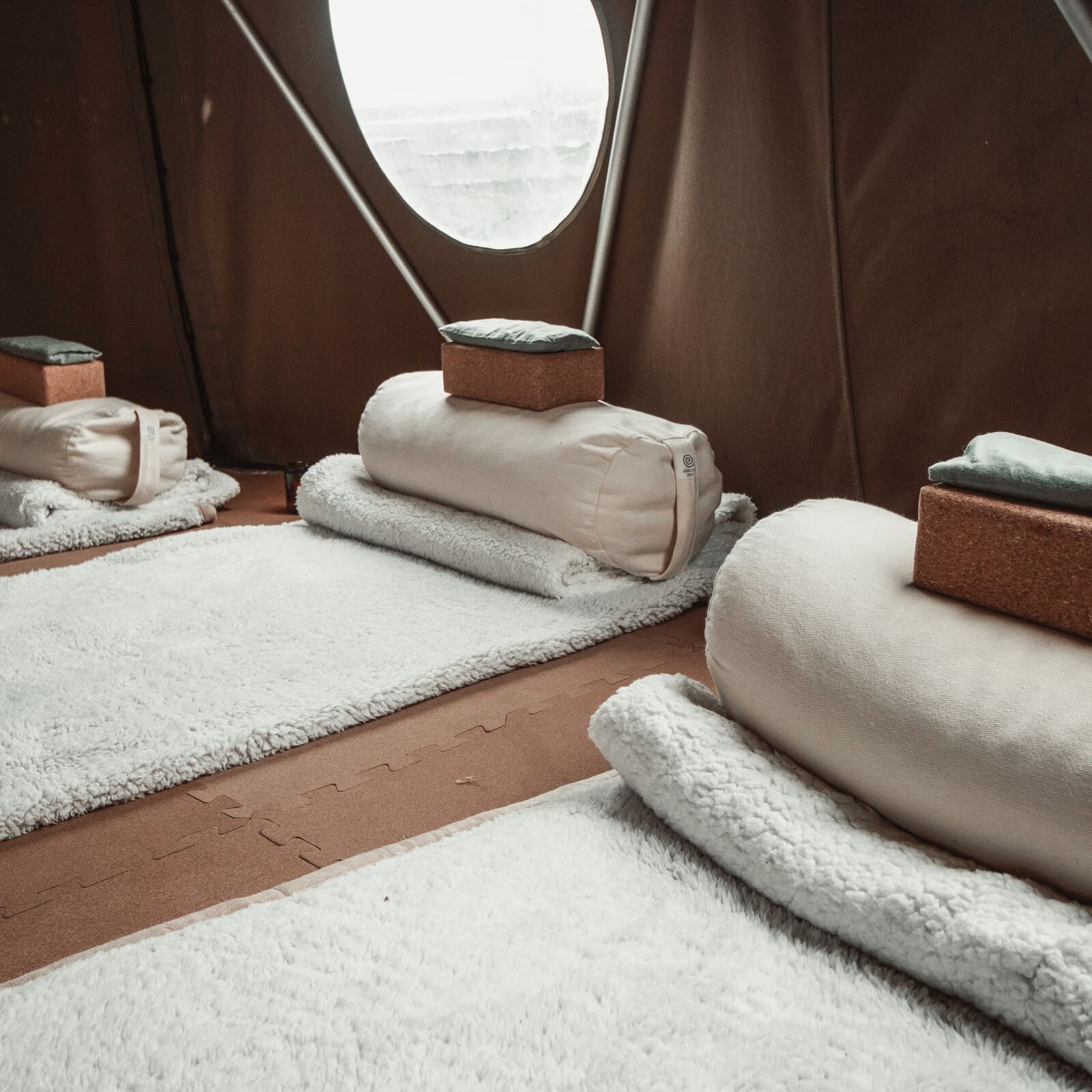 Three neatly prepared mats inside the Soul Sweats holistic health tent, each set with folded blankets and cork yoga blocks in soft natural light.
