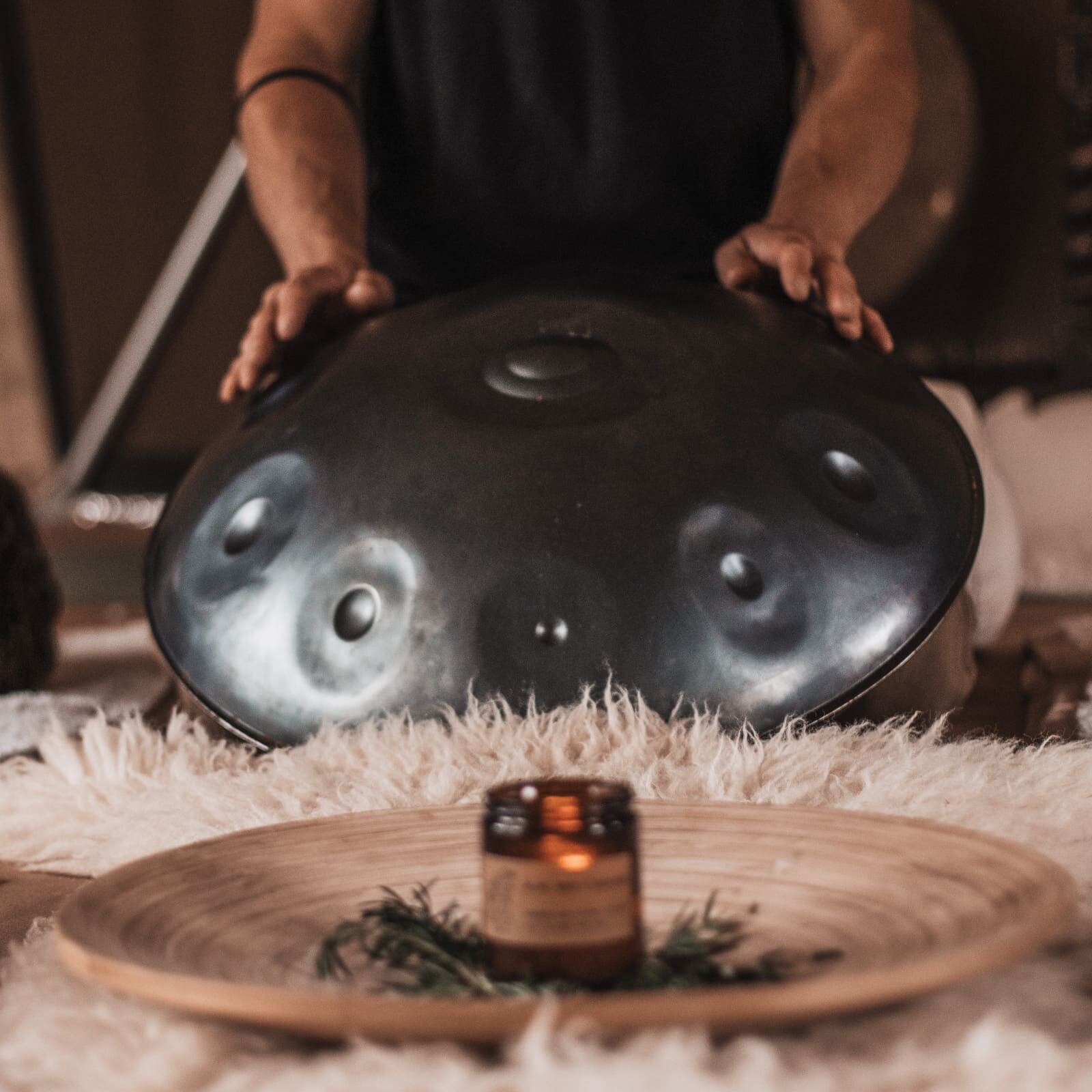 Practitioner playing a handpan during a Soul Sweats sound healing session, with participants resting on mats and eye pillows in a calming tented space.