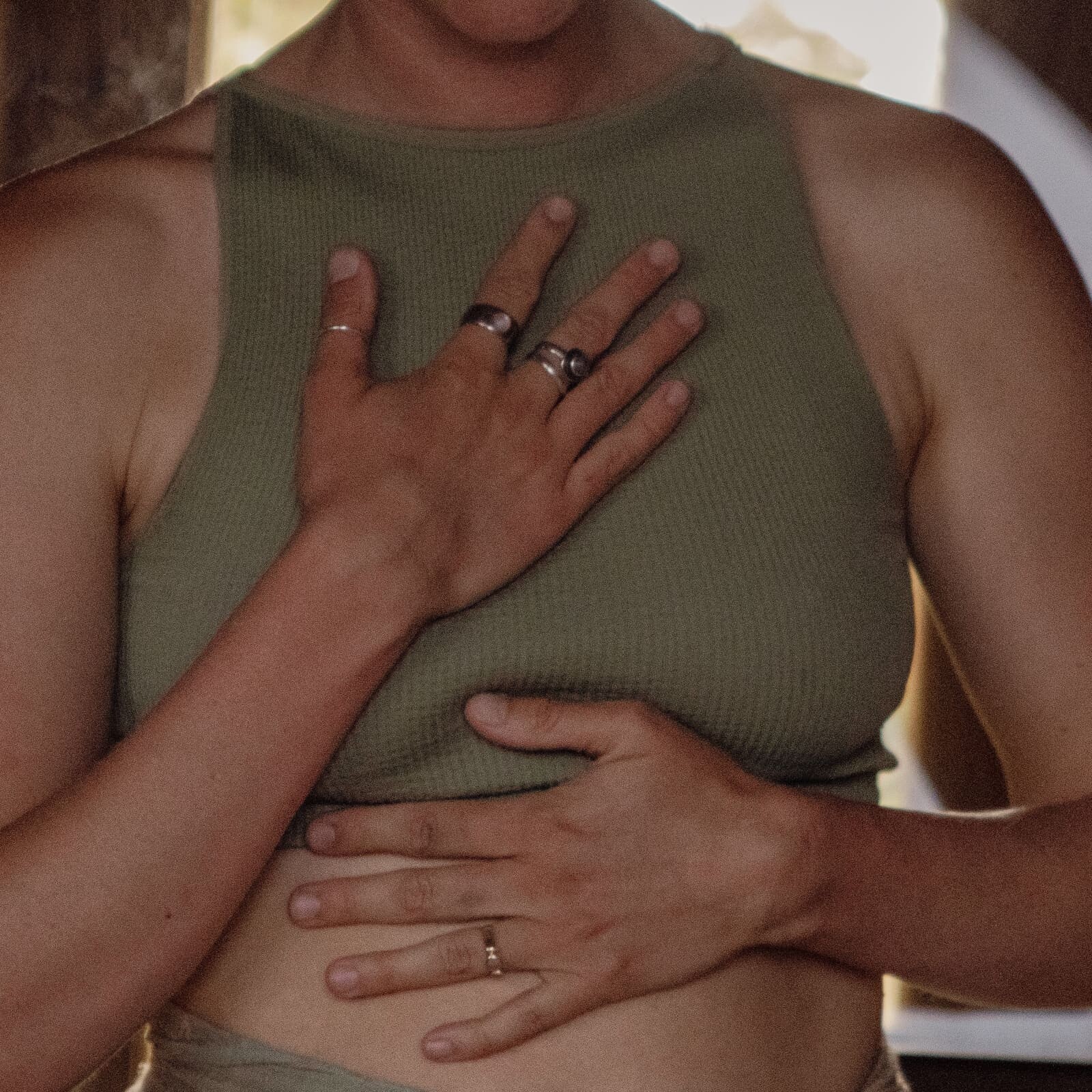 Person standing inside the Soul Sweats sauna with one hand on their chest and one on their stomach during a calming breathwork practice.